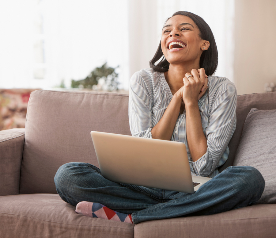 Young woman excited sitting on sofa with laptop