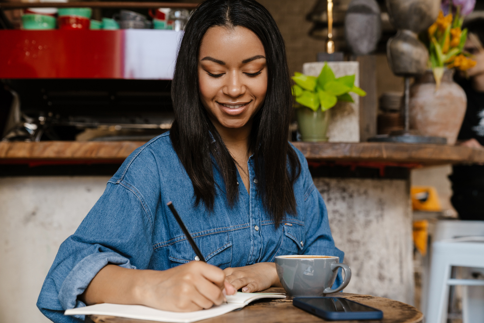 Smiling Young African Woman Writing in Notebook