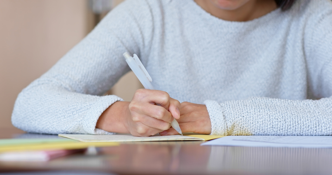 Woman Writing on Notebook at Home