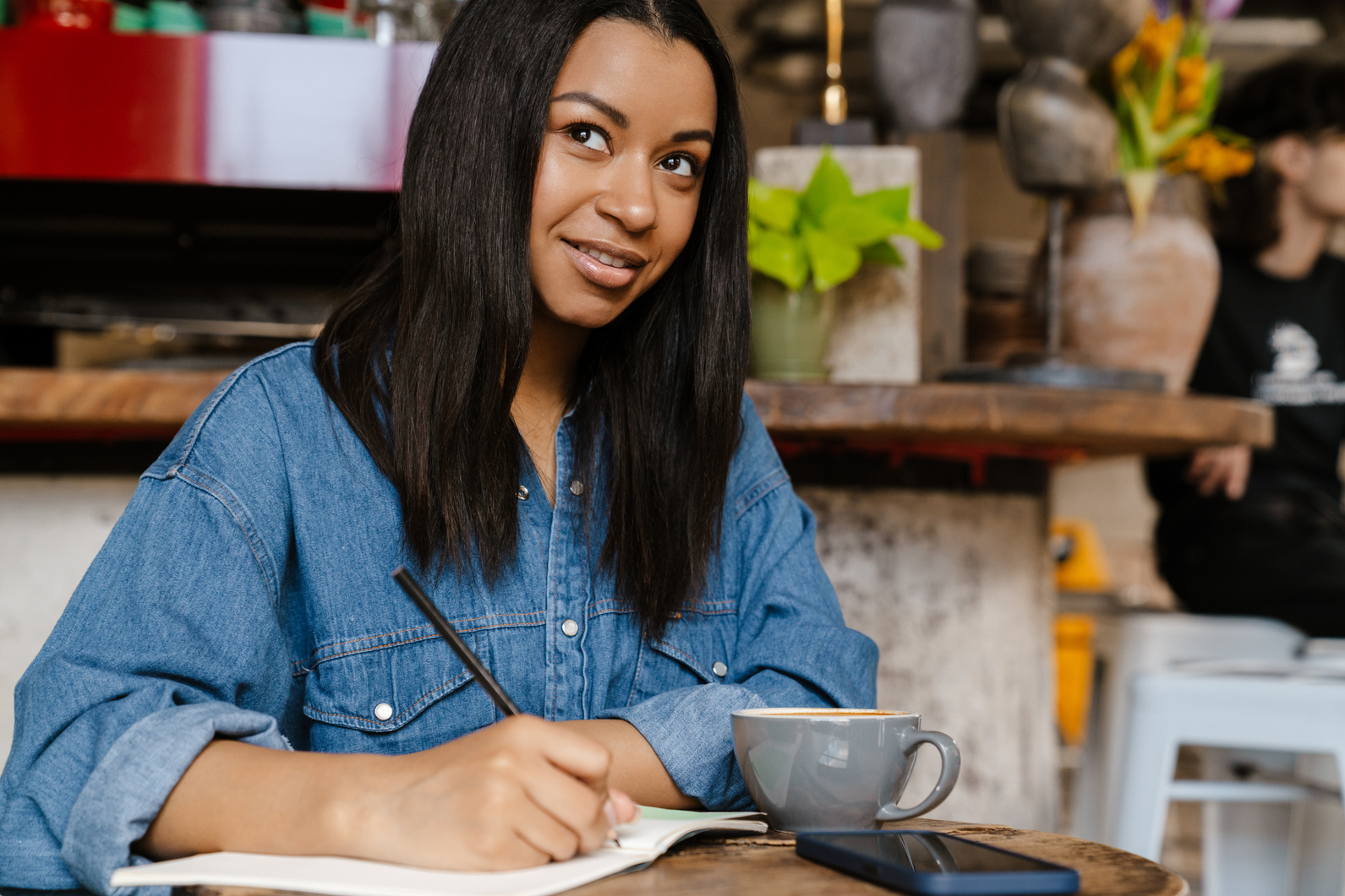 Smiling Young African Woman Writing in Notebook