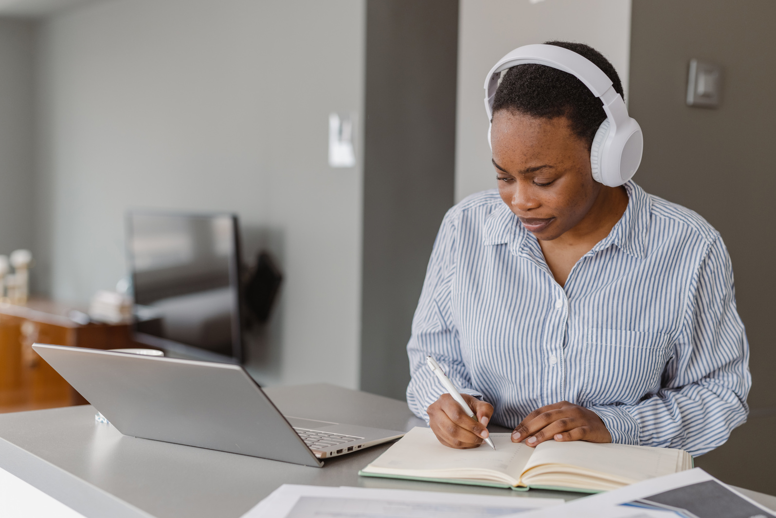 African-American woman with short hair using laptop and listening to online course