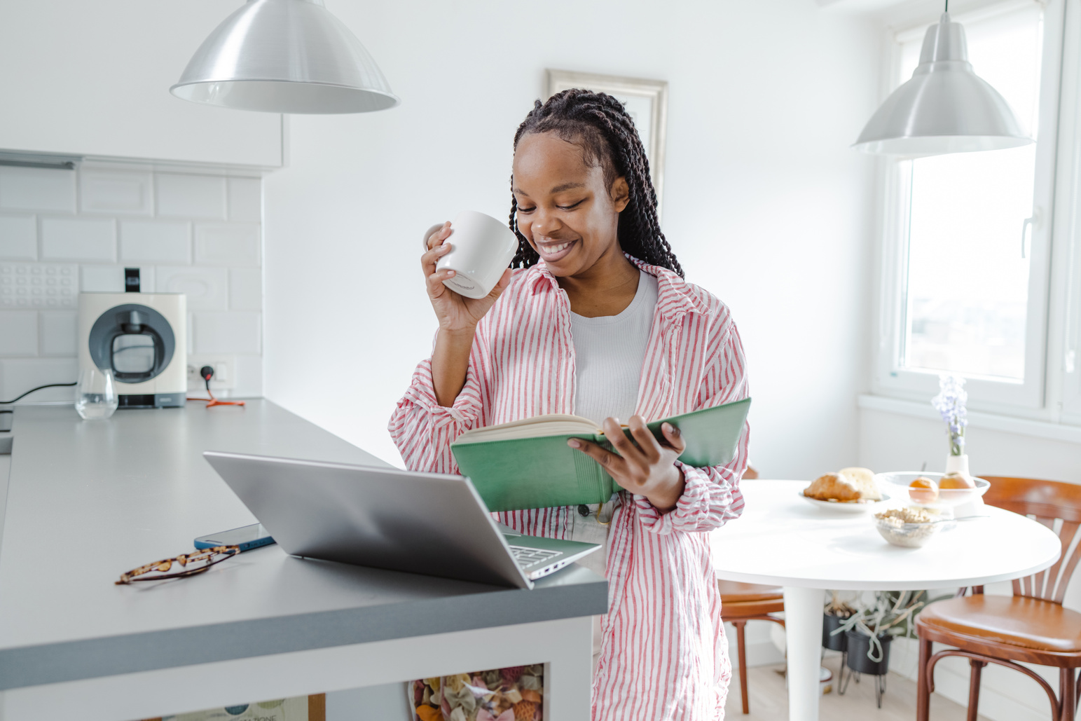 Cheerful African-American woman using laptop and listening to online course at home