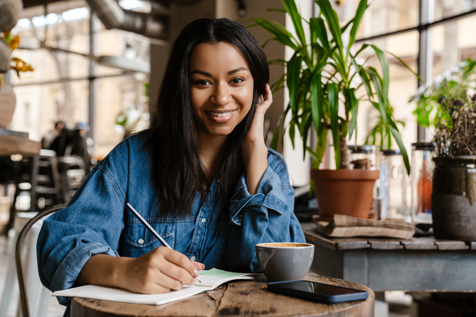 Smiling Young African Woman Writing in Notebook